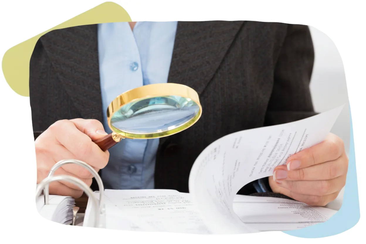 A close-up of a person performing Compliance Checks for Remire, examining a stack of paperwork through a gold-rimmed magnifying glass.