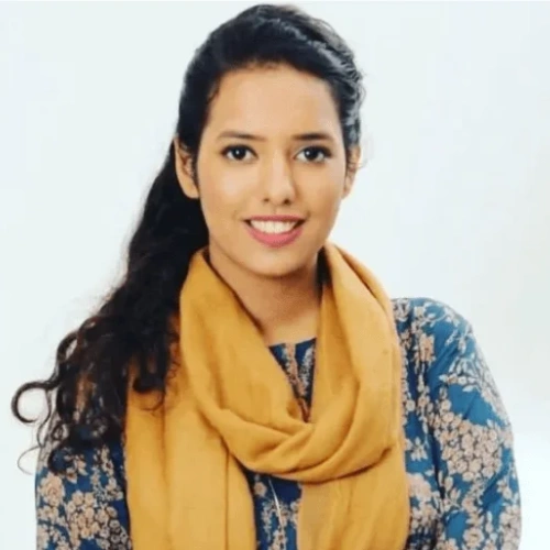 A professional headshot of Madiha Shamim Founder & CEO at Remire, smiling and wearing a mustard yellow scarf over a blue floral pattern dress.