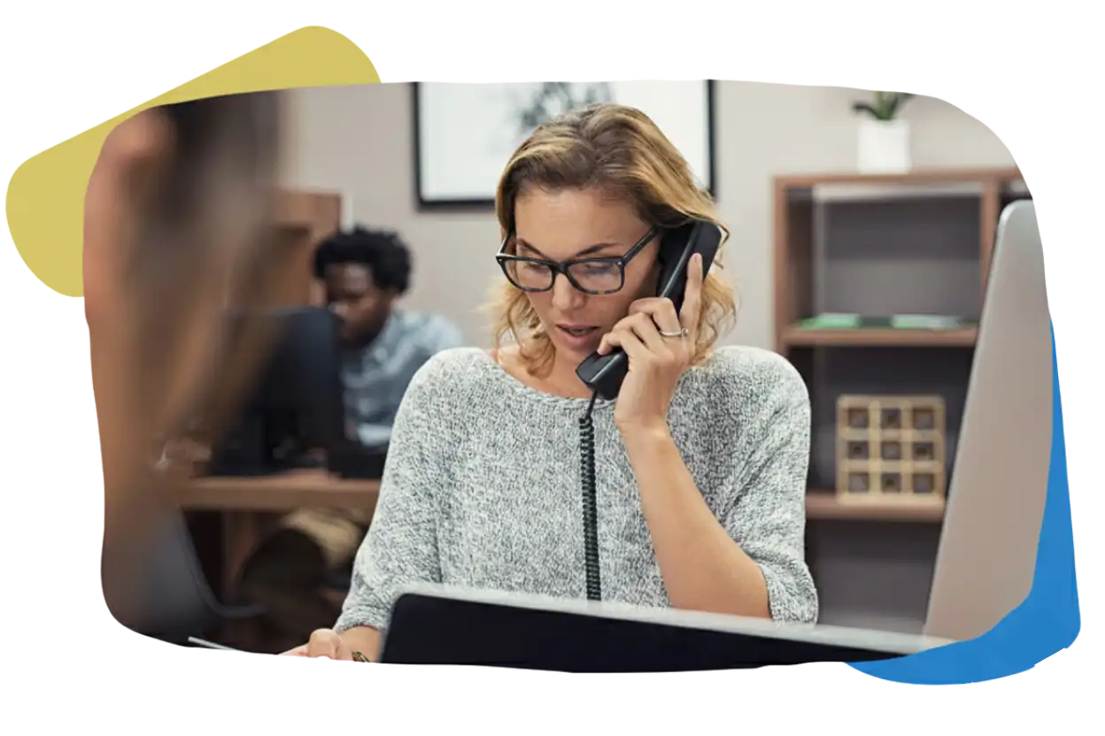 A focused woman with glasses handling a phone call at her desk, representing the dedicated Ongoing Support team at Remire.