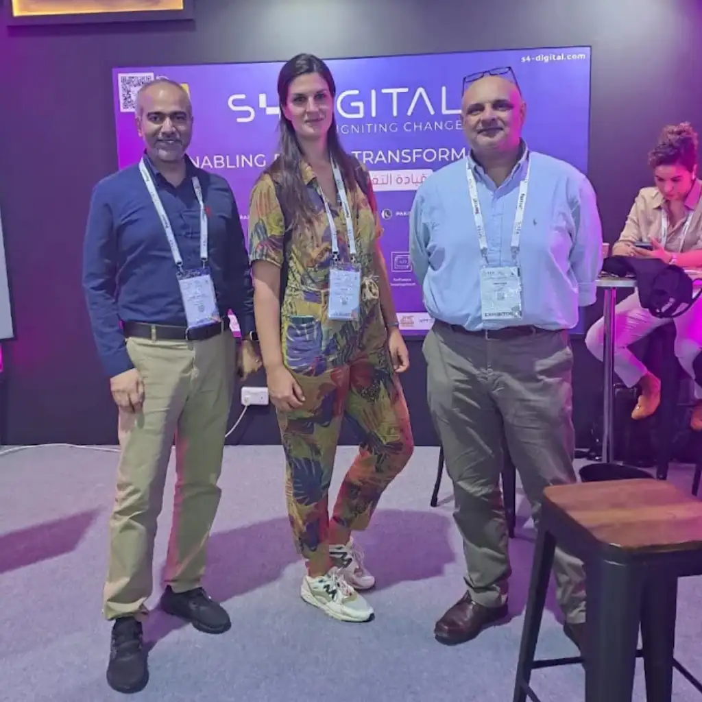 Three professional colleagues standing in front of an S4 Digital event backdrop, illustrating that Remire expanded EOR and contractor services.