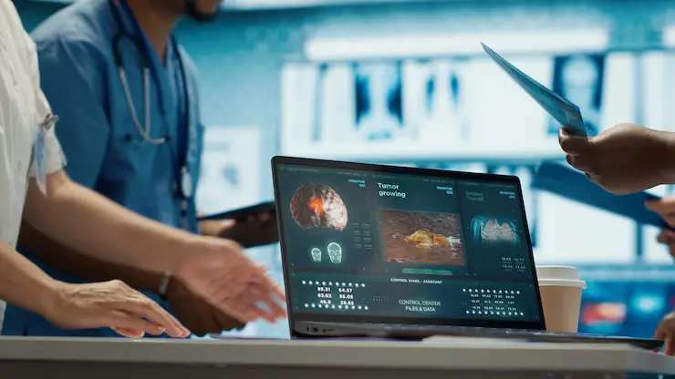 Remire supporting a modern Health Tech Company with advanced digital tools, showcasing a laptop screen that displays medical imaging and tumor analytics charts in a clinical setting.